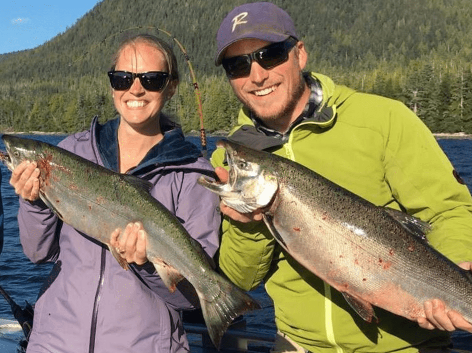 A man and a woman holding wild alaskan salmon during a Ketchikan Fishing Company salmon exursion.