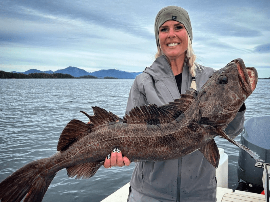 A woman holding a huge lingcod that she caught during a Ketchikan Fishing Company charter.