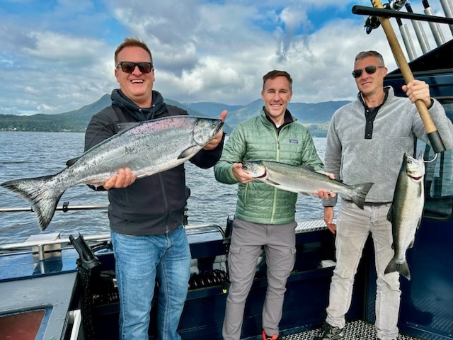 A group of Cruise guests fishing in Ketchikan Alaska holding huge salmon.
