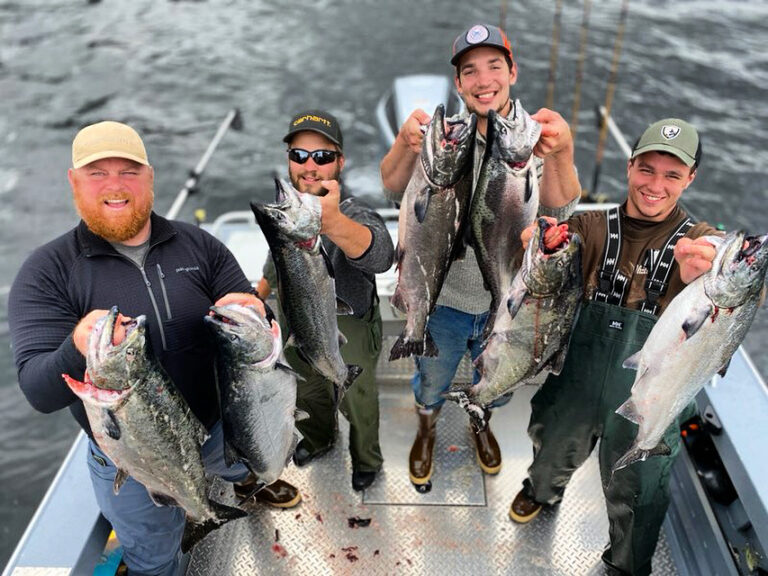 A group of 4 ketchikan lumberjacks that are holding wild alaskan salmon caught in ketchikan.