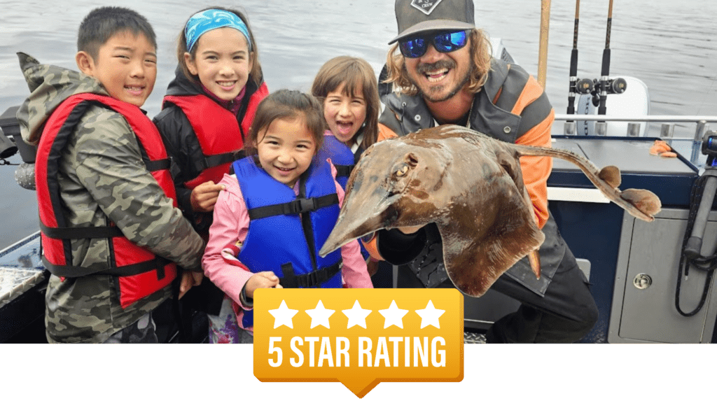 Owner, Captain Lukas, holding a skate fish with 4 kids behind him during a ketchikan fishing company excurison.