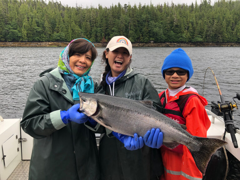 A family of 3 holding a wild alaskan salmon they caught during a ketchikan salmon fishing charter.