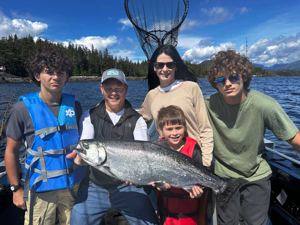A family holding a wild alaskan king salmon they caught during a ketchikan fishing company excursion.