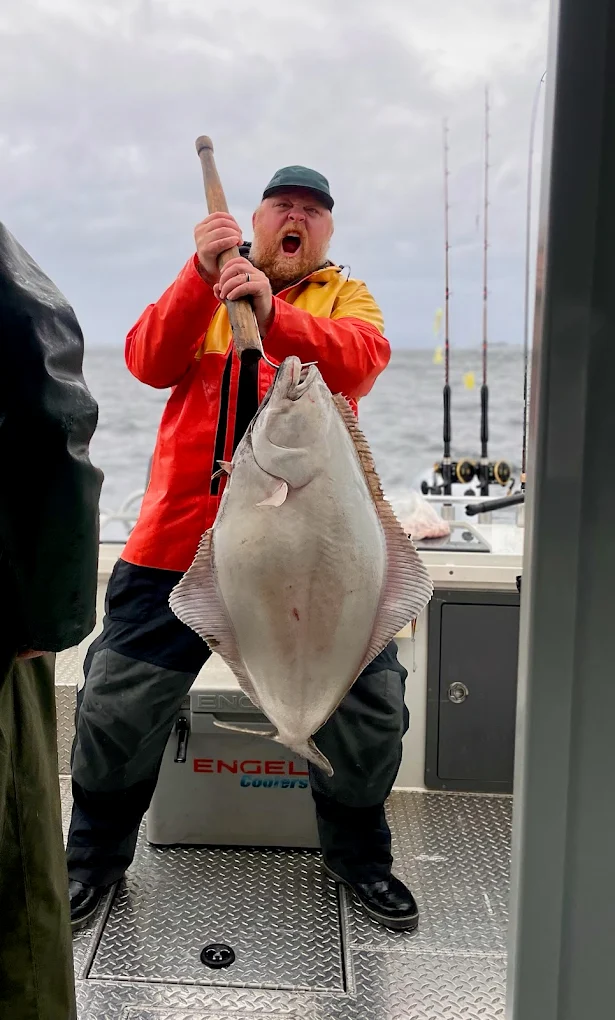 Captain Jake holding a huge pacific halibut that was caught during a ketchikan fishing charter.