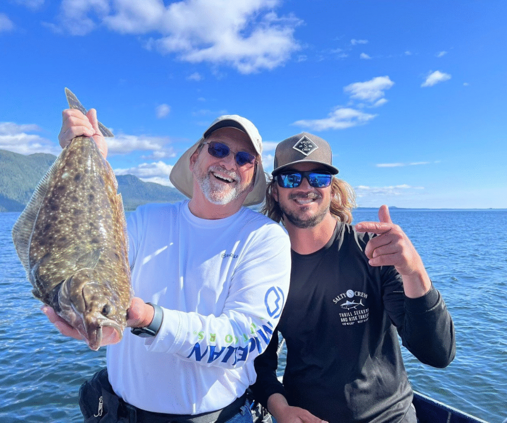 Captain Lukas of Ketchikan Fishing Company standing next to a first time angler holding a massive halibut