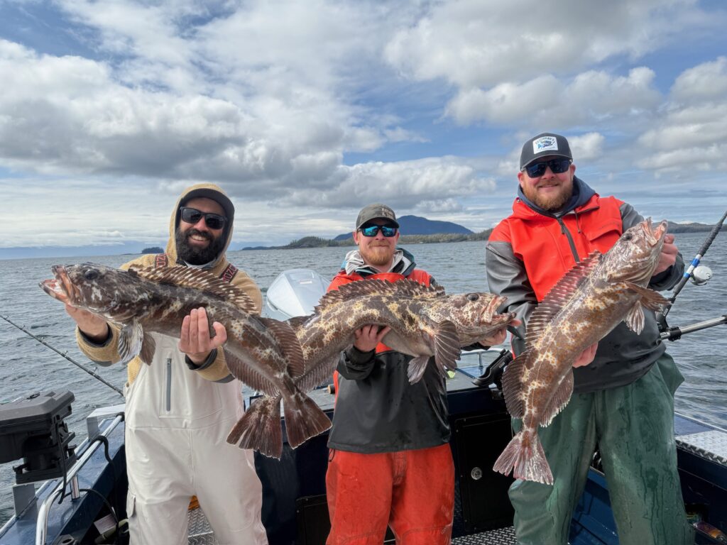 Captain Grayson and Captain Tony, the best fishing guides in ketchikan, holding massive fish standing on a boat on a sunny day.