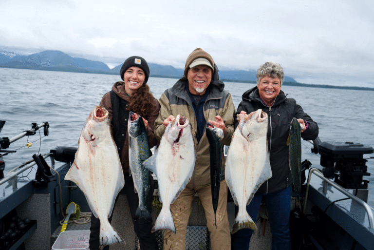 A group of happy anglers holds up their huge halibut caught during a guided fishing trip in Ketchikan, Alaska on a cloudy day—an unforgettable part of their cruise.