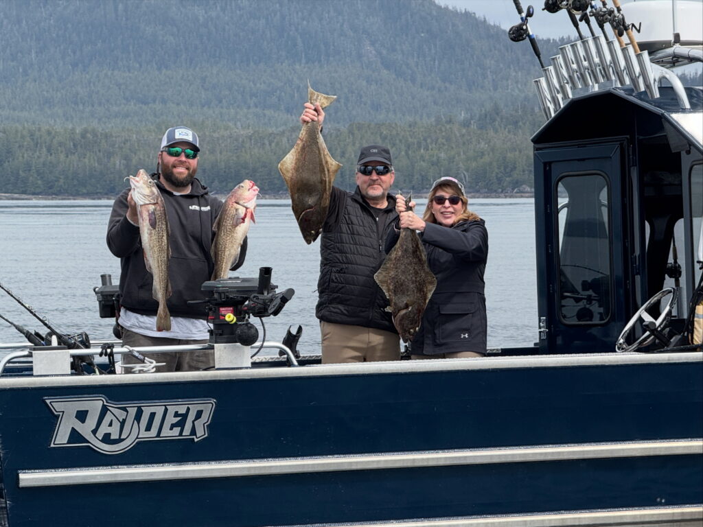 A group of guests standing on a boat with calm water in the background on a cloudy day